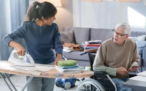 A caregiver is helping an old disable people in household task.