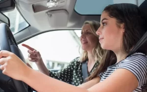 A specialized driving trainer is giving driving instruction to young lady.